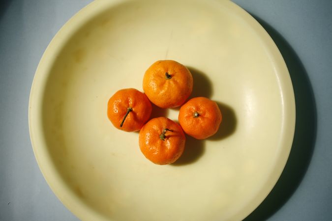Looking down at four clementines on a plate