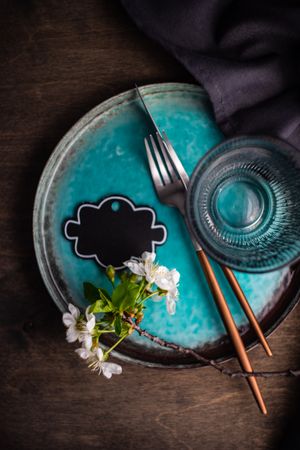 Top view of teal plate in spring table setting with light buds
