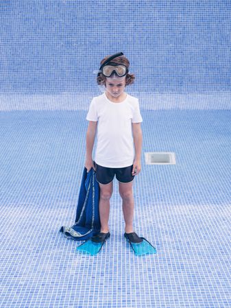 Sad boy in flippers and mask in empty pool