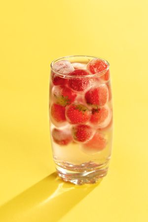 Frozen baby strawberries in a glass of water