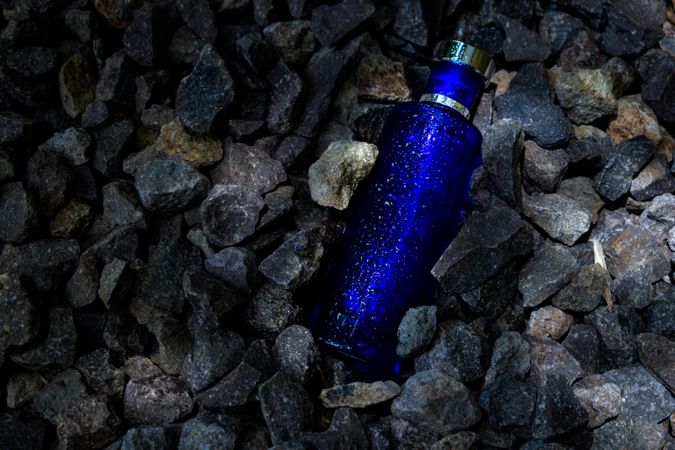 Blue perfume bottle mock up laying in rocky terrain