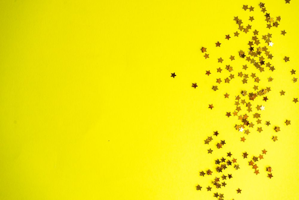 Festive xmas card concept of star glitter on yellow background