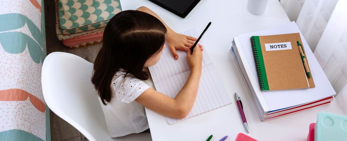 Girl studying at home with tablet and mask on table
