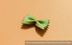 Spinach farfalle pasta minimalist on an orange table 5leoN4