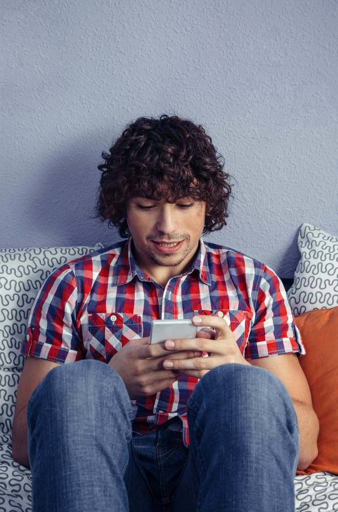 Young handsome man looking at smartphone relaxing in bed