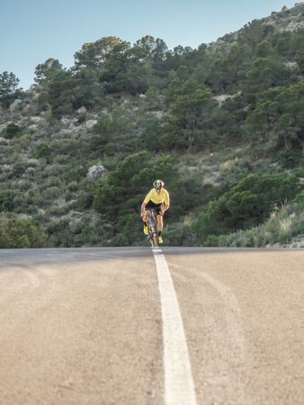 healthy man riding a bicycle on a mountain road in a sunny day