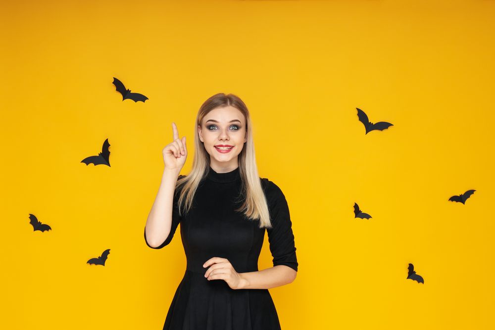 Concept of Halloween, young woman on yellow background