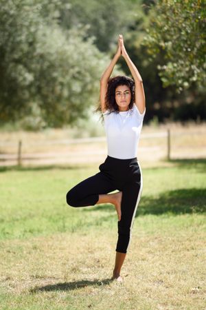 Arab woman doing one legged yoga pose in field