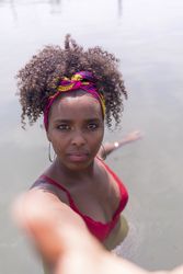 Young woman on vacation in the water reaching towards camera