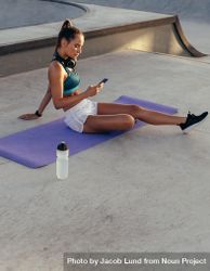 Woman checking her fitness performance on mobile phone after workout 5oEV9b