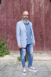 Front view of a mature trendy bearded hipster standing against a vintage red door outdoors while looking to camera