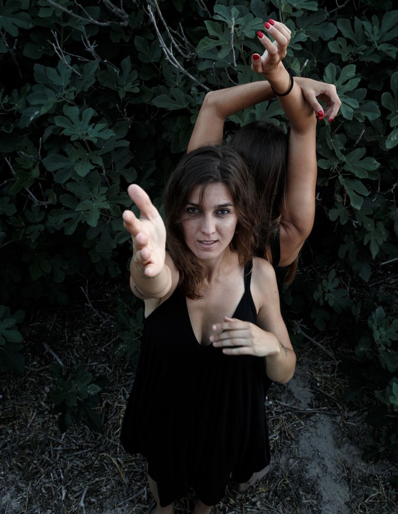 Young women posing near green bush