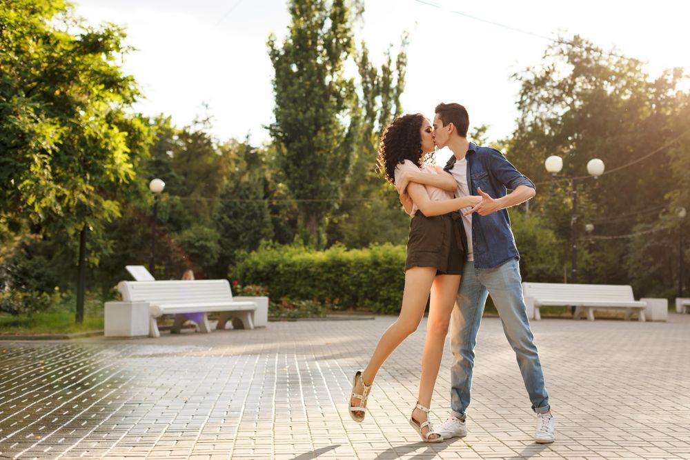 Teenagers on a date kissing in sunny street