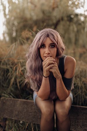 Modern woman sitting on wooden fence