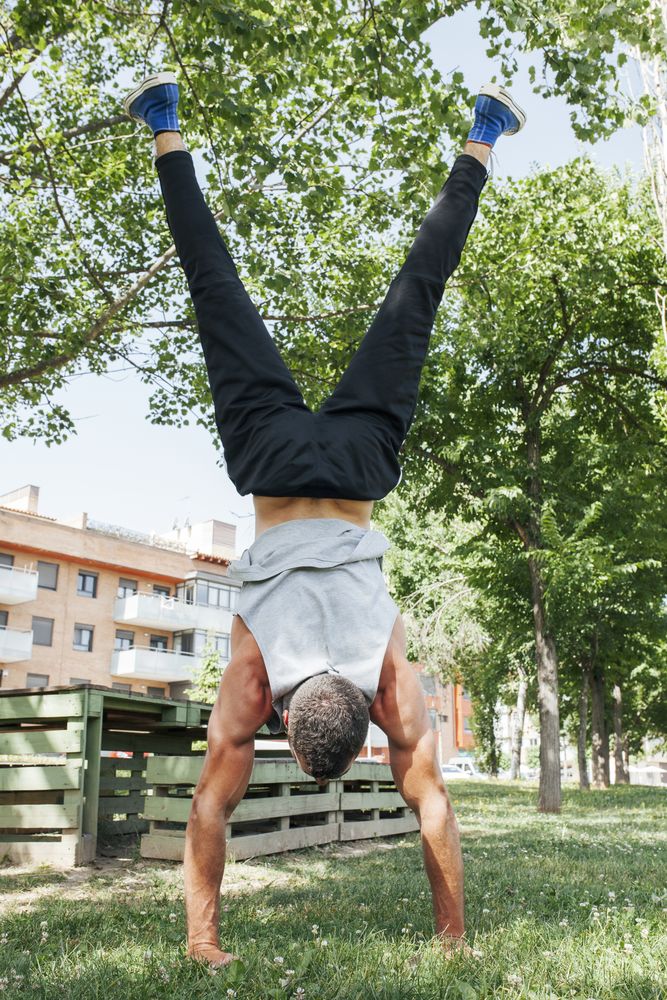 Sportsman standing on hands in park