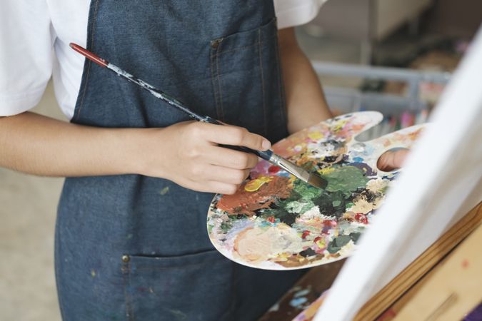 Young Asian female artist painting on canvas doing art projects on her studio.