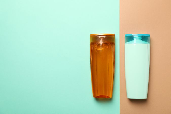 Blank bottles of shampoo on two tone background, space for text