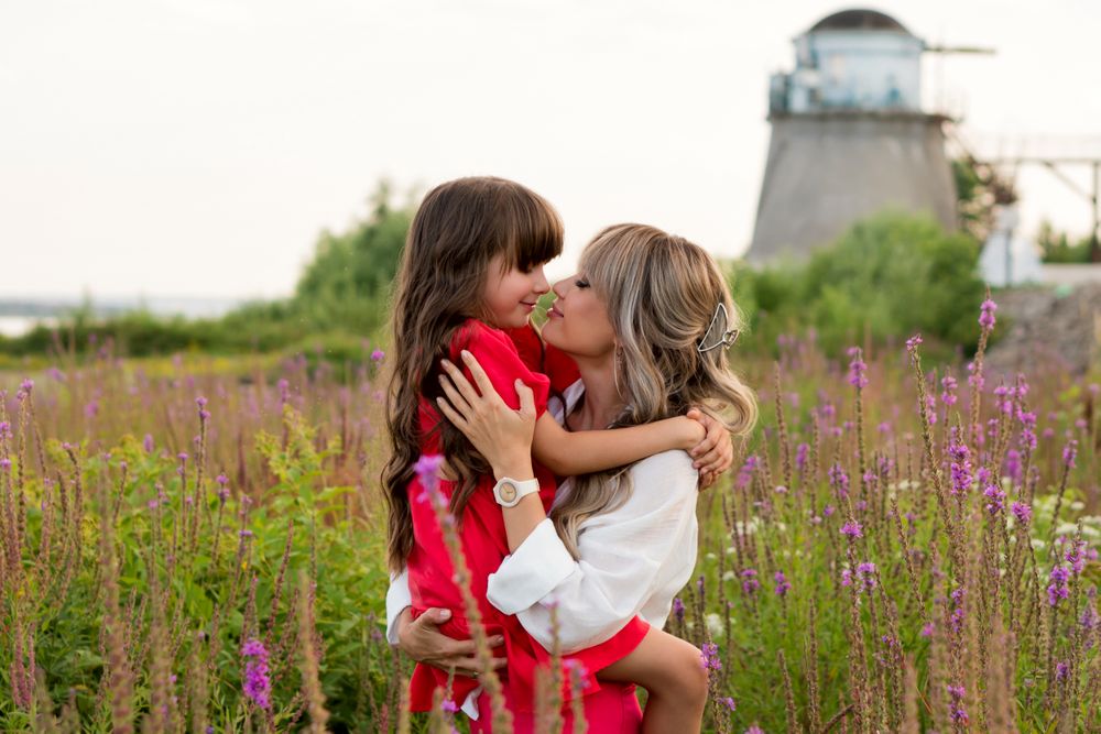 Mom and little daughter walking among meadow flowers