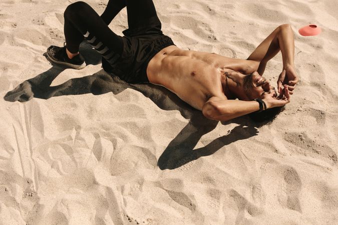 Top view of a shirtless man relaxing during workout at a beach