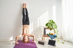 Shirtless child closing eyes in headstand in light room