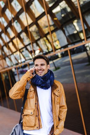 Stylish guy using smartphone outside modern building