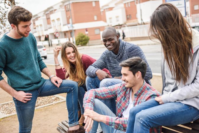 Multi-ethnic friends chatting on bench outside