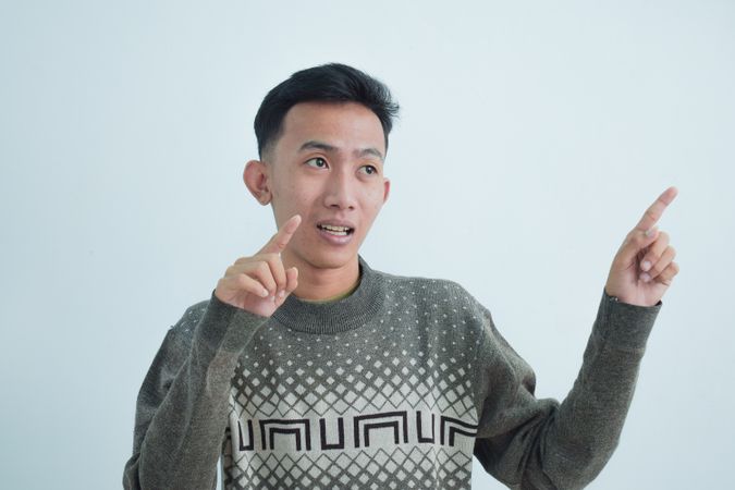 Asian man pointing in studio