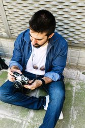 Man setting up phone while sitting on pavement outside