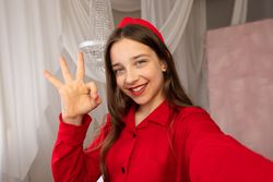 Teen girl smiling taking selfie showing okay hand gesture...