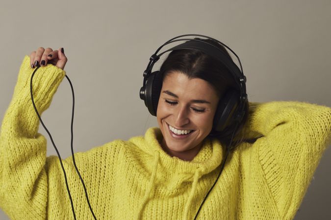 Playful young woman listening to music in studio