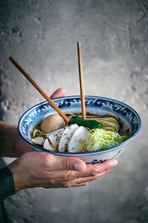 Crop man with bowl of tasty ramen and chopsticks