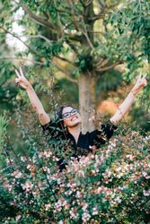 Smiling female looking out of green bushes