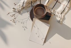 Cup of coffee and checkered plaid on table with mockup card