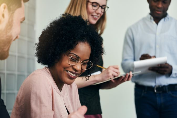 Woman smiling while her colleagues takes notes at work