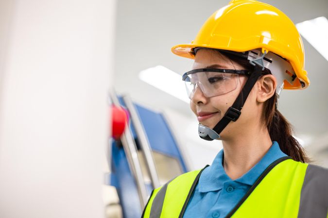 Portrait of Asian worker woman or engineer in safety helmet operating technology
