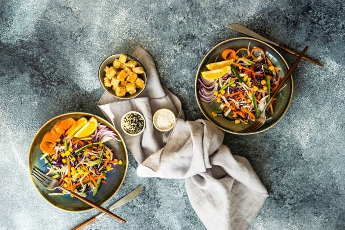 Top view of two healthy colorful vegetable salad and croutons in bowl on counter with copy space