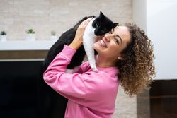 Happy woman hugging cute cat at home
