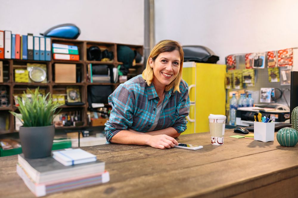 Portrait of happy blonde woman entrepreneur looking at camera in local motorbike shop.