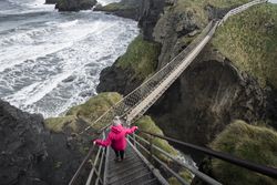 Woman crossing rope bridge leading to rocky island