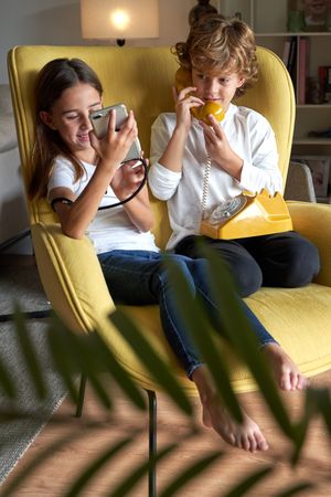 Content children using old telephone and new smartphone