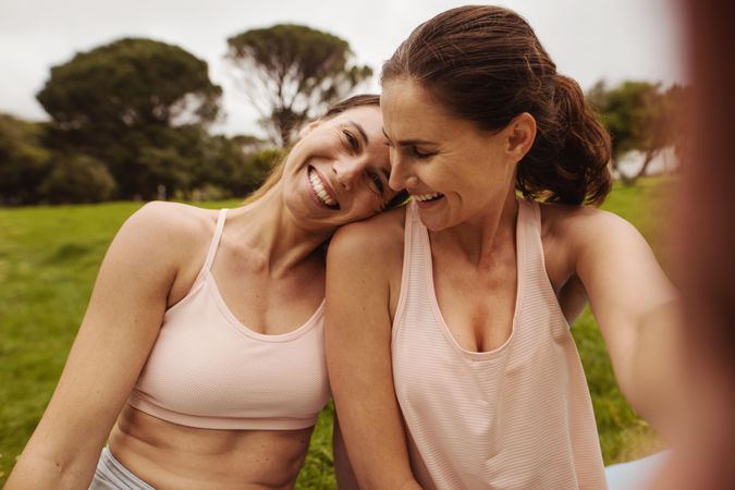 Close up of two smiling females relaxing after workout outdoors