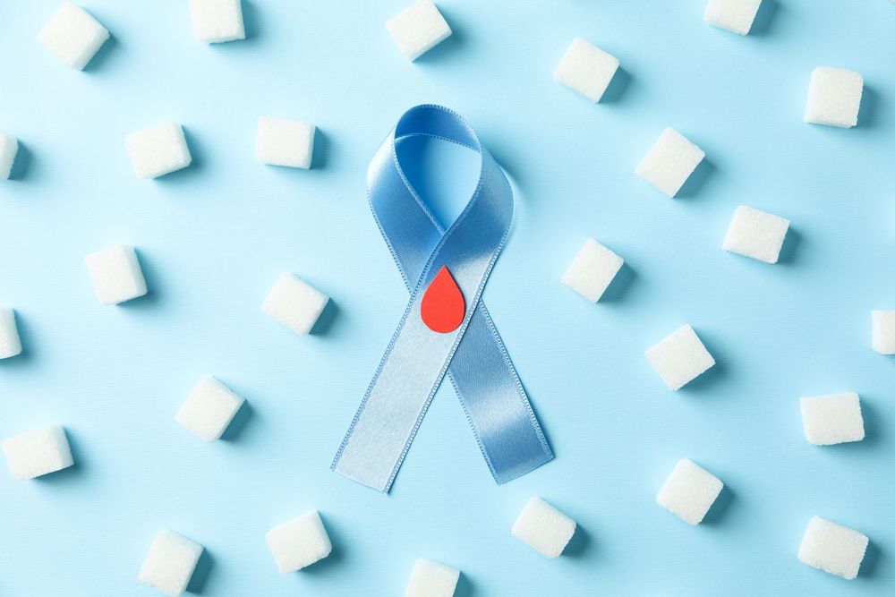 Diabetes awareness ribbon and sugar cubes on blue background