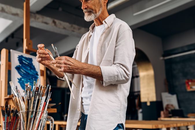 Man with grey beard choosing which paint brush to use