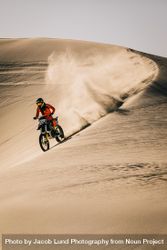 Dirt biker riding over sand dunes 5QLO90