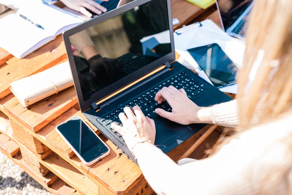 Detail of hands working with computers,notes and mobile phones on a wooden table.Business and study.