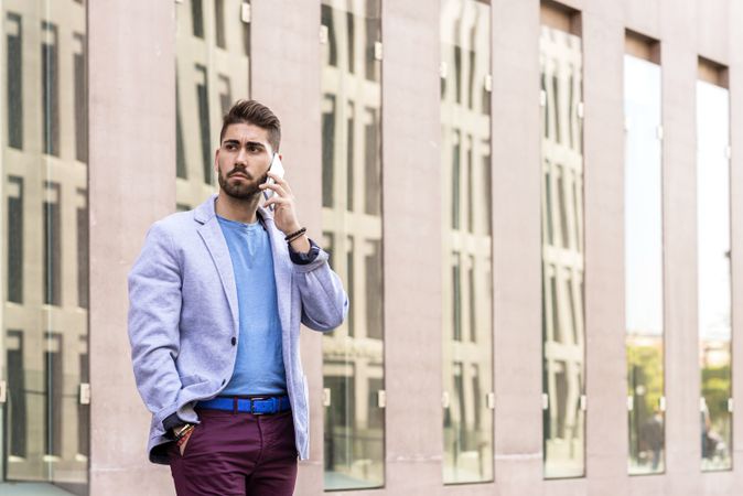 Portrait of cheerful modern businessman speaking by phone while standing outdoors
