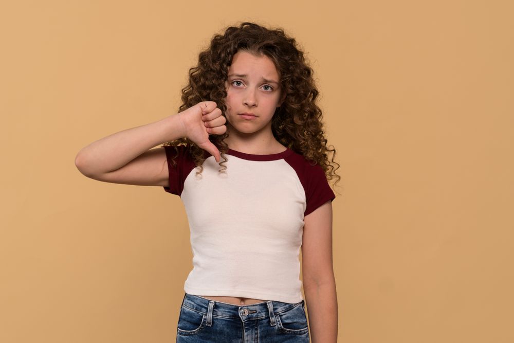 Young girl giving thumbs-down gesture, showing disapproval