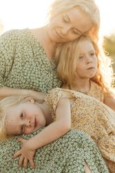 Calm mother embracing daughters in sunlight