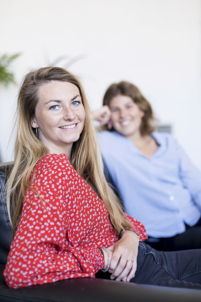 Two happy young female friends enjoying a conversation in the living room at home