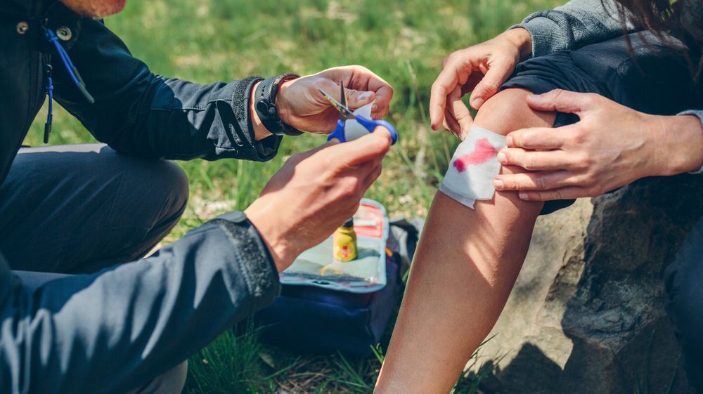 Man healing knee to woman who has been injured trekking